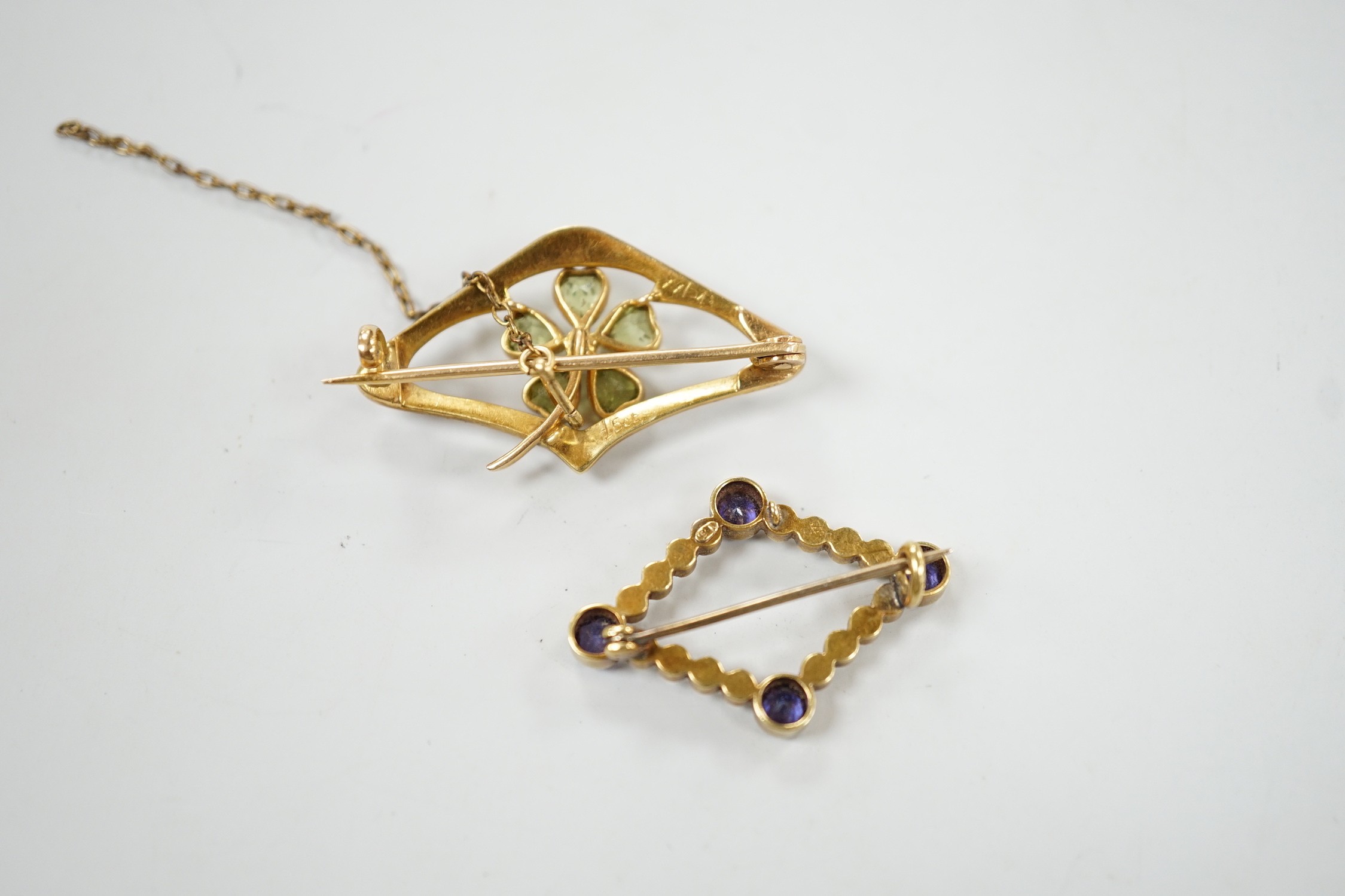An Edwardian 15ct, peridot and seed pearl set brooch, 36mm and a similar sapphire and split pearl set brooch, gross weight 8.1 grams.